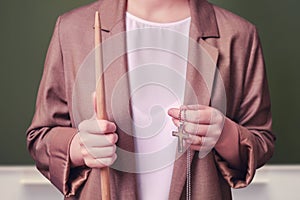 Woman teacher holding religious symbol catholic cross on school blac