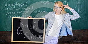 Woman teacher holds blackboard back to school inscription on chalkboard background. Apply for sensational educational