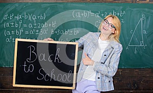 Woman teacher holds blackboard back to school inscription on chalkboard background. Apply for sensational educational