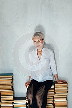 Woman teacher and stacks of books in school library