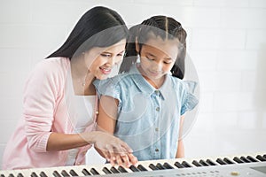 Woman teacher teach piano a girl