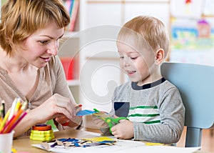 Woman teaches child handcraft at kindergarten or playschool or home photo