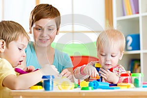 Woman teaches children handcraft at kindergarten or playschool photo