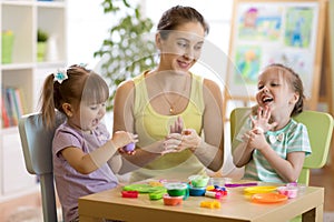 Woman teaches children modeling plasticine in day care center