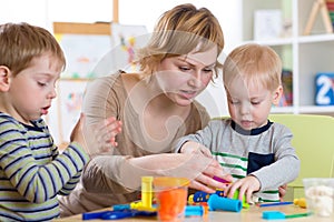 Woman teaches kids handcraft at kindergarten or playschool photo