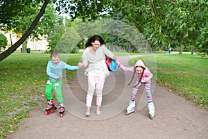 Woman teaches laughing children to roller skate in the Park