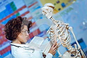 Woman teaching anatomy using human skeleton model