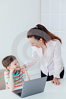 Woman teaching boy on laptop in school classroom