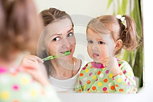 Woman teaching child daughter teeth brushing in