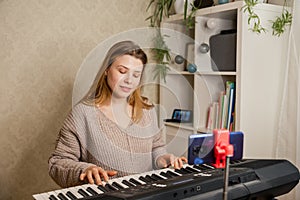 Woman teaching her student to play piano and recording lesson online.