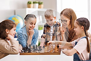 Woman teaching kids to play chess at school