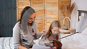 Woman Teaching Little Girl to Play Violin Indoors