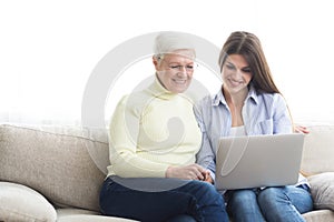 Woman teaching mother how to use laptop computer