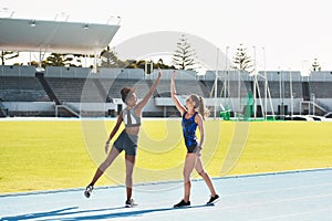 Woman, team and high five on stadium track for running, exercise or training together in athletics outdoors. Women
