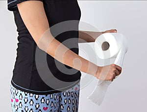 Woman tearing tissue from toilet paper roll