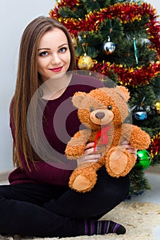 Woman with teddy bear near the Christmas tree