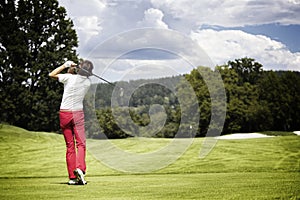 Woman teeing-off golf ball.