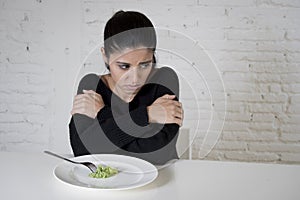 Woman or teen with fork eating dish with ridiculous little lettuce as her food symbol of crazy diet