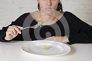 Woman or teen with fork eating dish with ridiculous little lettuce as her food symbol of crazy diet