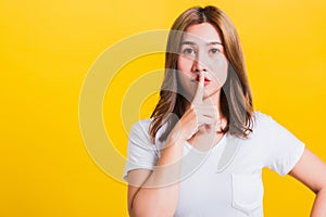 Woman teen smile standing wear t-shirt making finger on lips silent quiet gesture