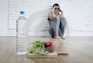 Woman or teenager girl sitting on ground alone worried at home suffering nutrition eating disorder