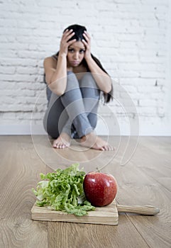 Woman or teenager girl sitting on ground alone worried at home suffering nutrition eating disorder