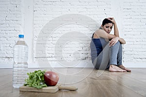 Woman or teenager girl sitting on ground alone worried at home suffering nutrition eating disorder