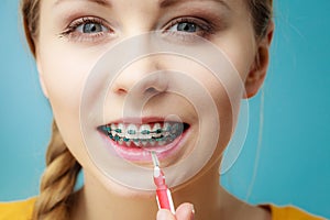 Woman with teeth braces using interdental brush