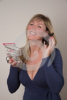 Woman with telephone holding a supermarket trolley