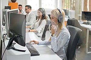 Woman telephone operator with headset working on computer in row in customer call support helpline business center