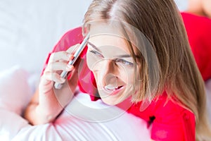 Woman telephoning on bed