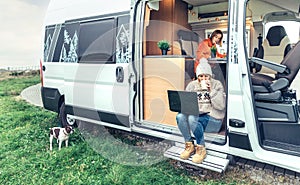 Woman teleworking drinking coffee sitting in the door of a camper van