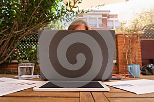 Woman teleworking from her home garden with laptop and tablet,