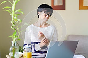 Woman teleworking from home with wrist pain having a massage to rest.