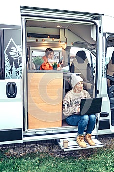 Woman teleworking sitting in the door of a camper van