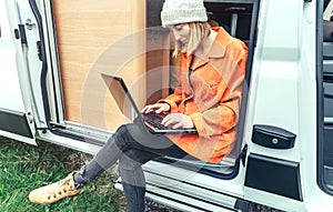 Woman teleworking sitting in the door of campervan