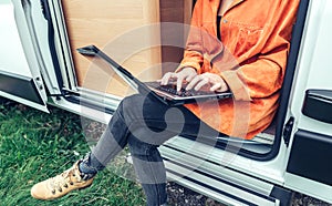 Woman teleworking sitting in the door of campervan