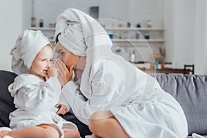 Woman telling secret to daughter while