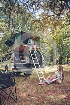 Woman in tent over car and other putting hiking boots