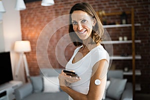 Woman Testing Glucose Level With Continuous Glucose Monitor