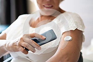 Woman Testing Glucose Level With Continuous Glucose Monitor