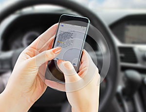 Woman texting while driving her car.