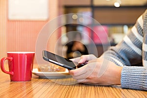 Woman texting message on cellphone at cafe