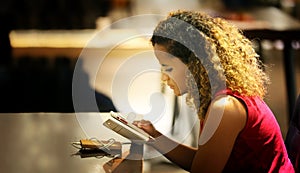 Woman texting on mobile phone in cafe.