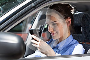 Woman texting on mobile phone at car