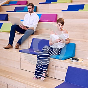 Woman texting on phone and man browsing with modern notebook