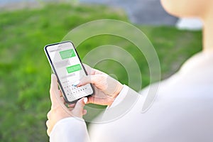 Woman texting with phone outdoors. Text message with smartphone. Digital sms and instant messaging chat. Person using cellphone.