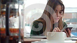 Woman texting, sending sms on smartphone in cafe