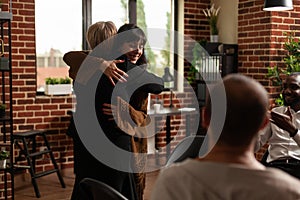 Woman and therapist hugging after sharing recovery progress with aa meeting group