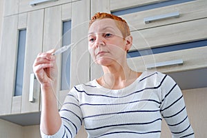 Woman with a thermometer in her hand. Elevated body temperature